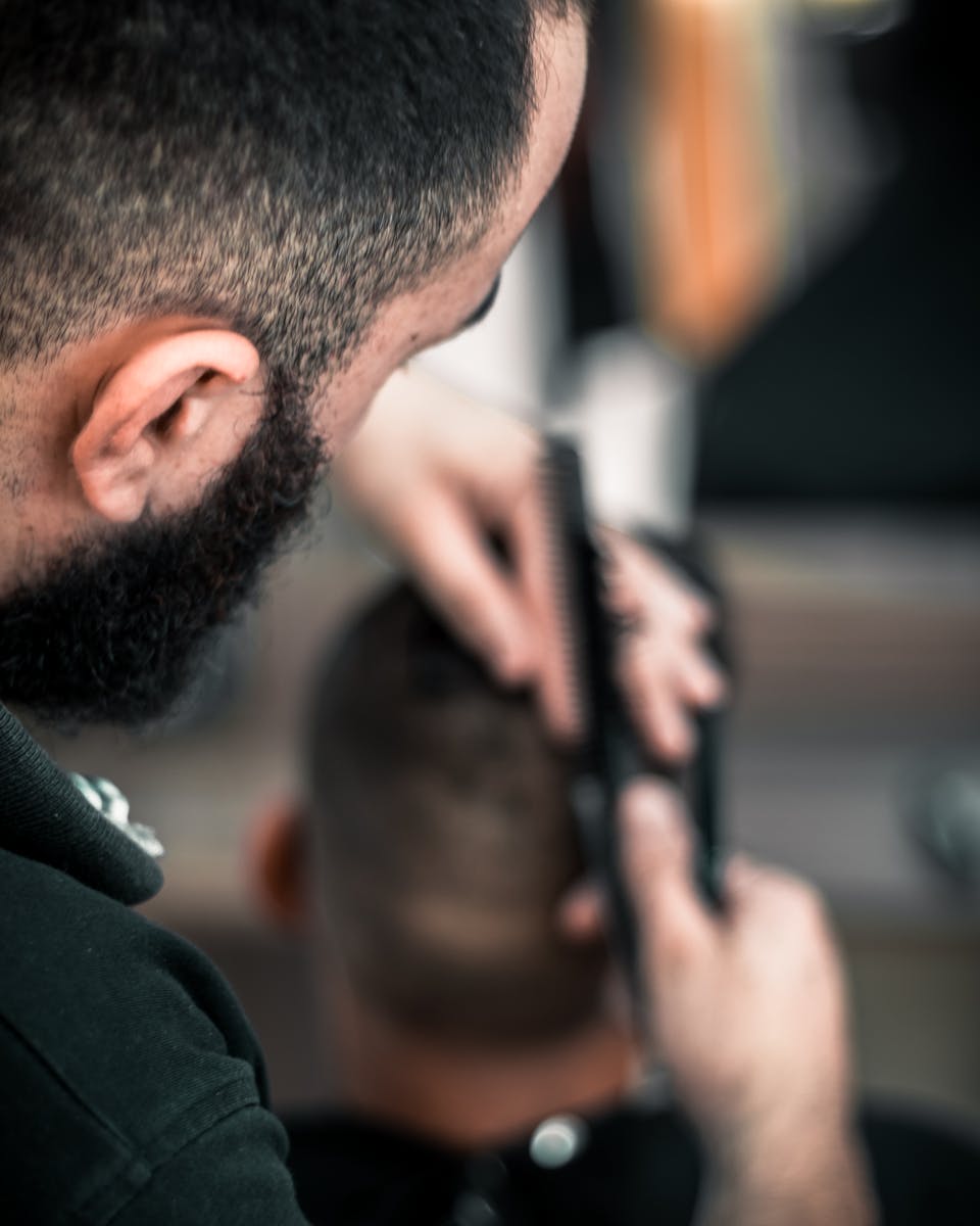 Close-up of a barber meticulously cutting a man's hair, focus on detail.