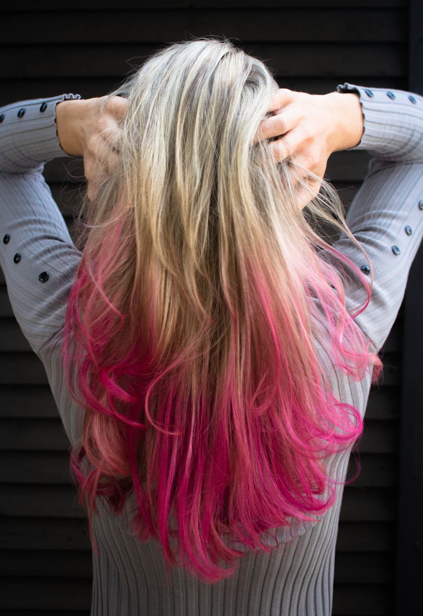 Close-up of a woman with blonde and pink ombre hair in a stylish pose.