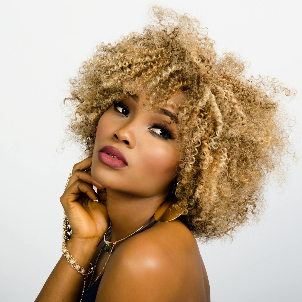 Elegant portrait of a woman with golden curly hair, showcasing beauty and confidence.