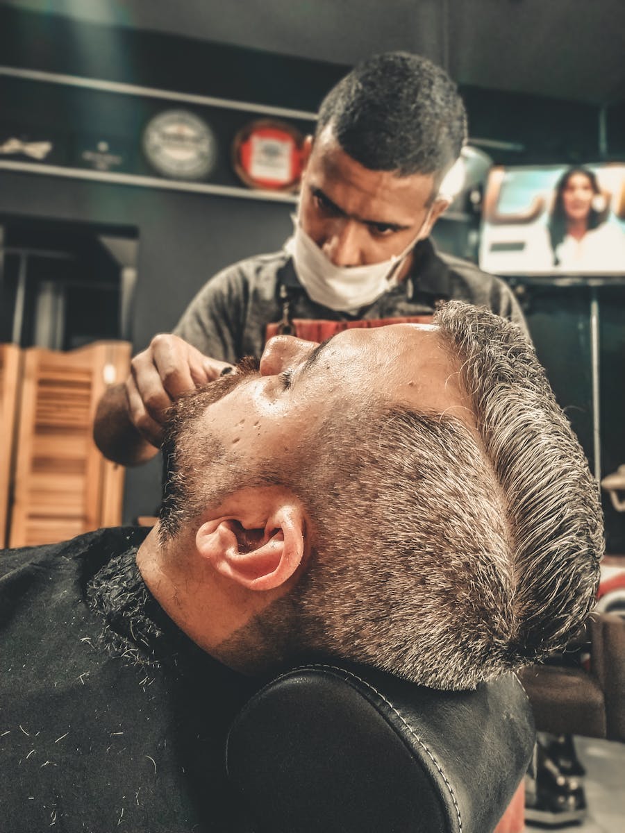 A barber skillfully provides a haircut and grooming at a modern barber shop, emphasizing professional care.