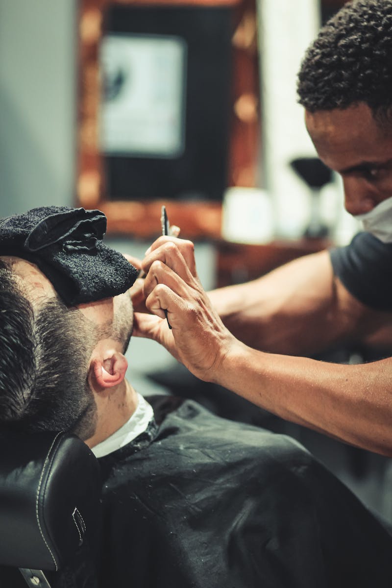 Barber skillfully trims client's beard in a modern barbershop setting.