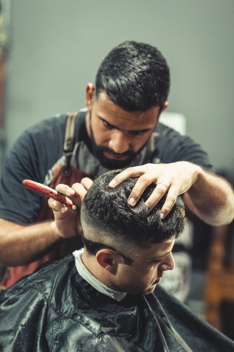 A professional barber expertly cutting a man's hair in a stylish barbershop setting.