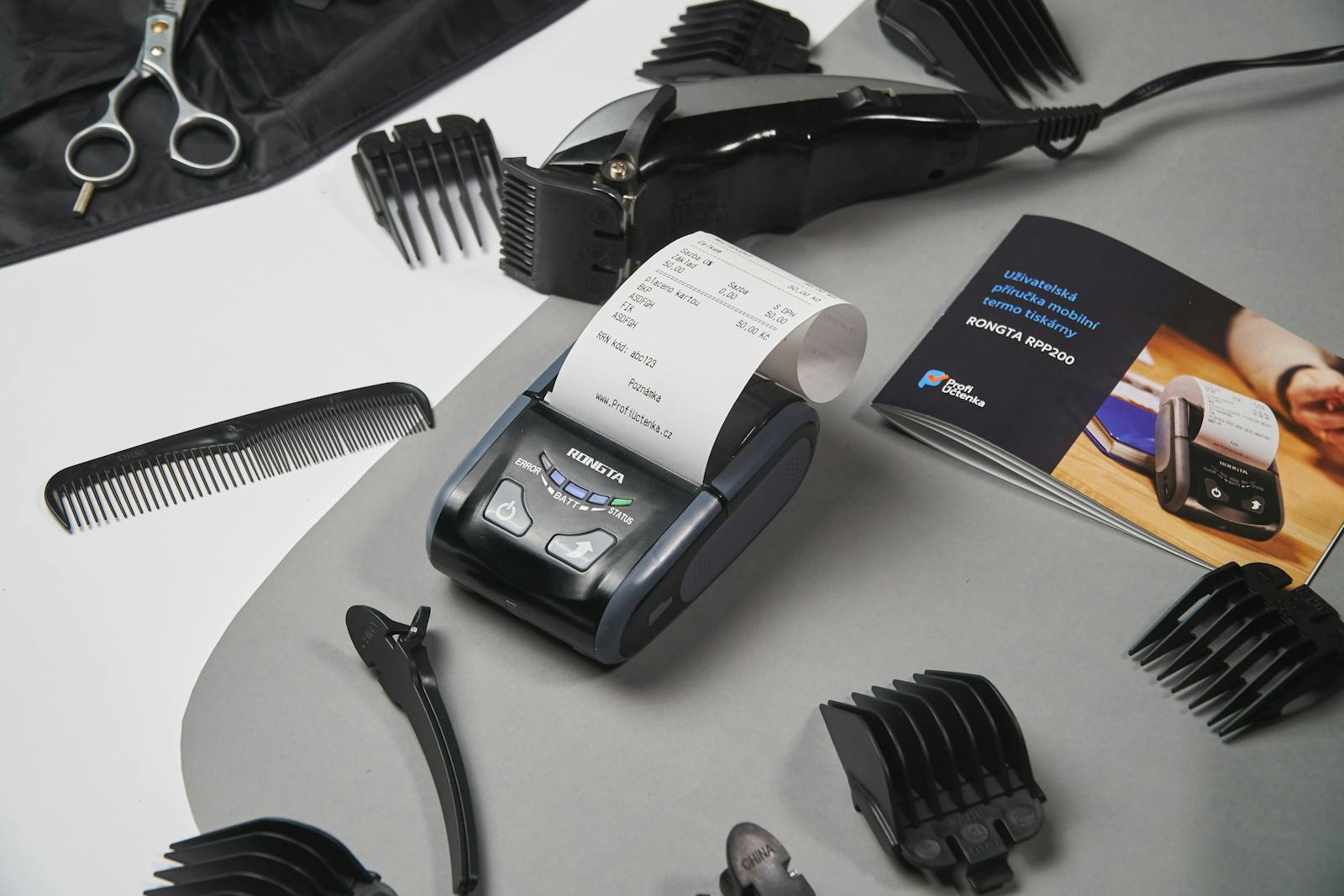 Overhead view of contemporary black cash register among modern clipper and manual composing with combs and hairpins on table in bright studio