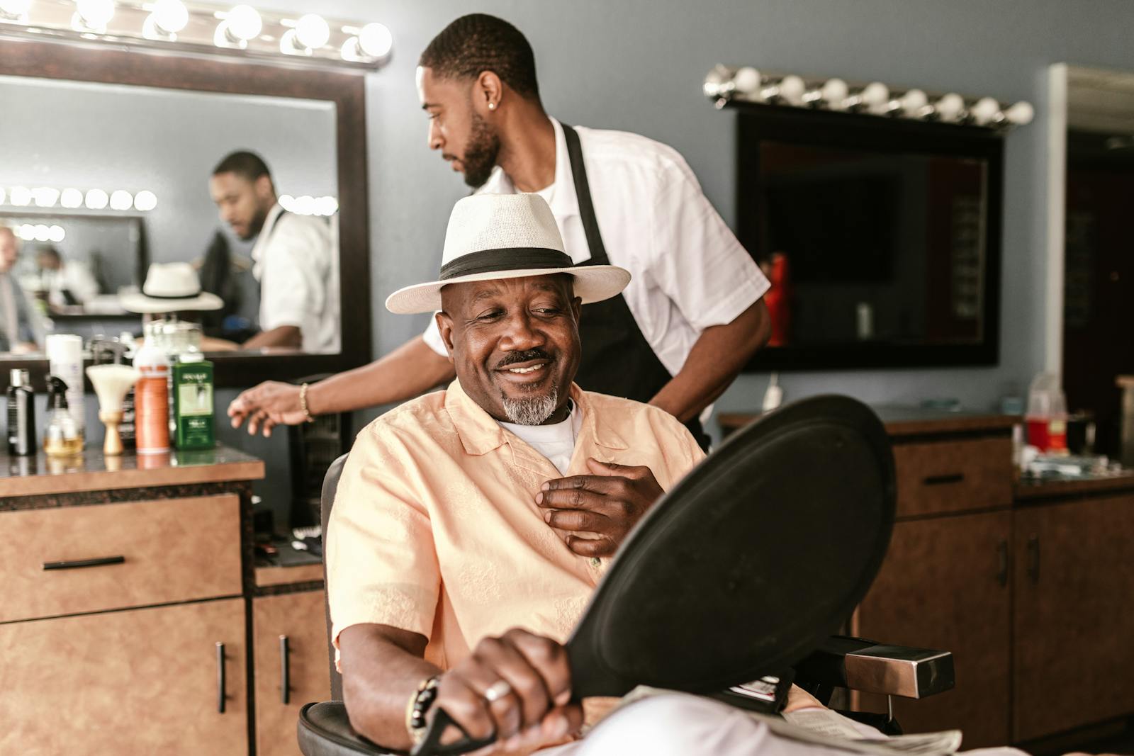 A happy customer enjoys a haircut in a stylish barber shop with a friendly barber.