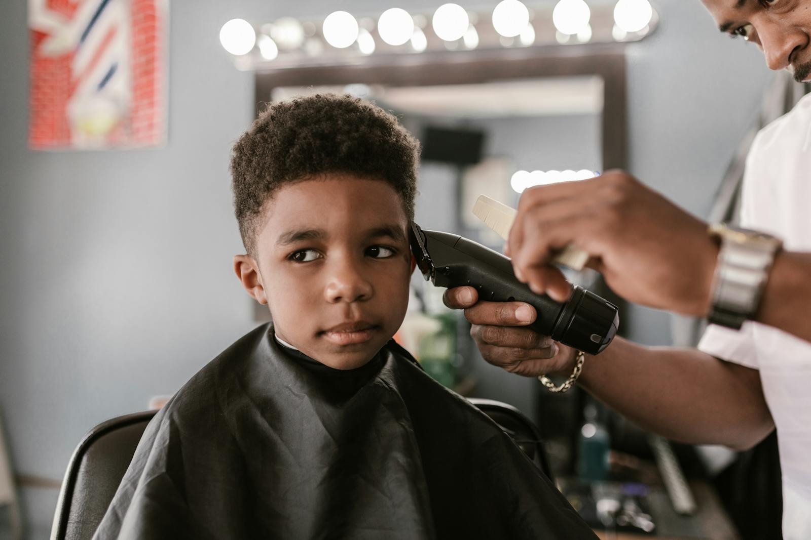 A young boy receives a haircut in an urban barbershop, capturing a moment of grooming.