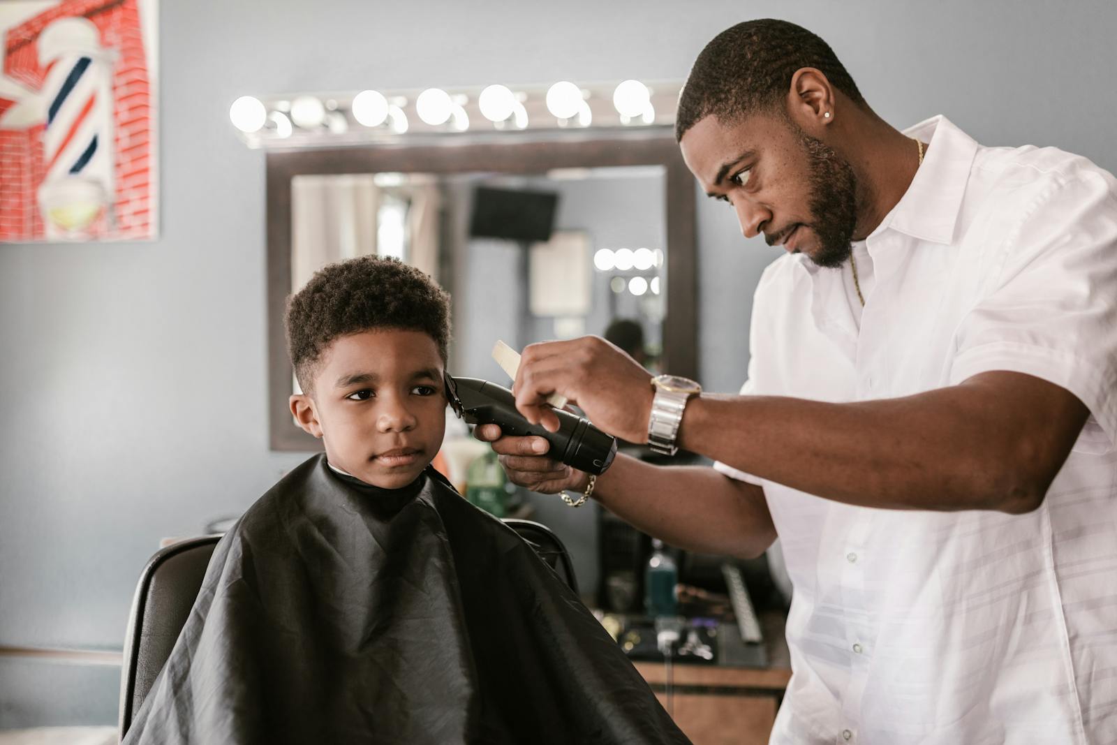 A skilled barber cuts a young boy's hair with precision in a modern barbershop.