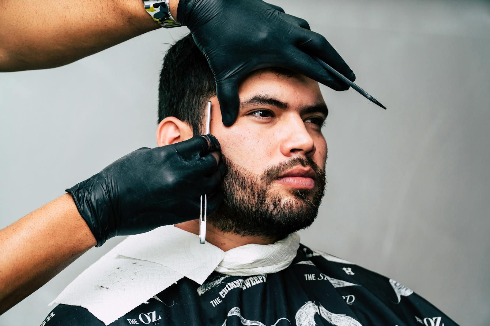 Man receiving a precise beard trim in a barbershop, showcasing expert grooming skills.