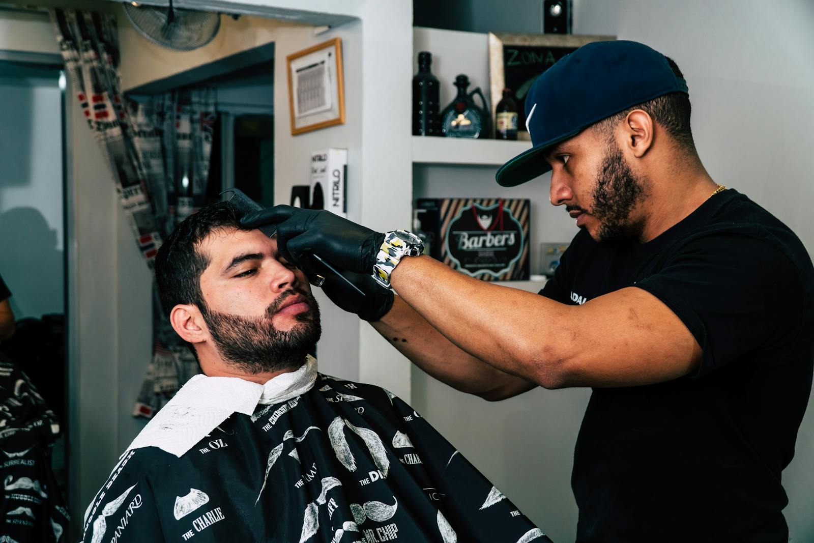 Barber skillfully trims client's hair in modern barbershop setting.