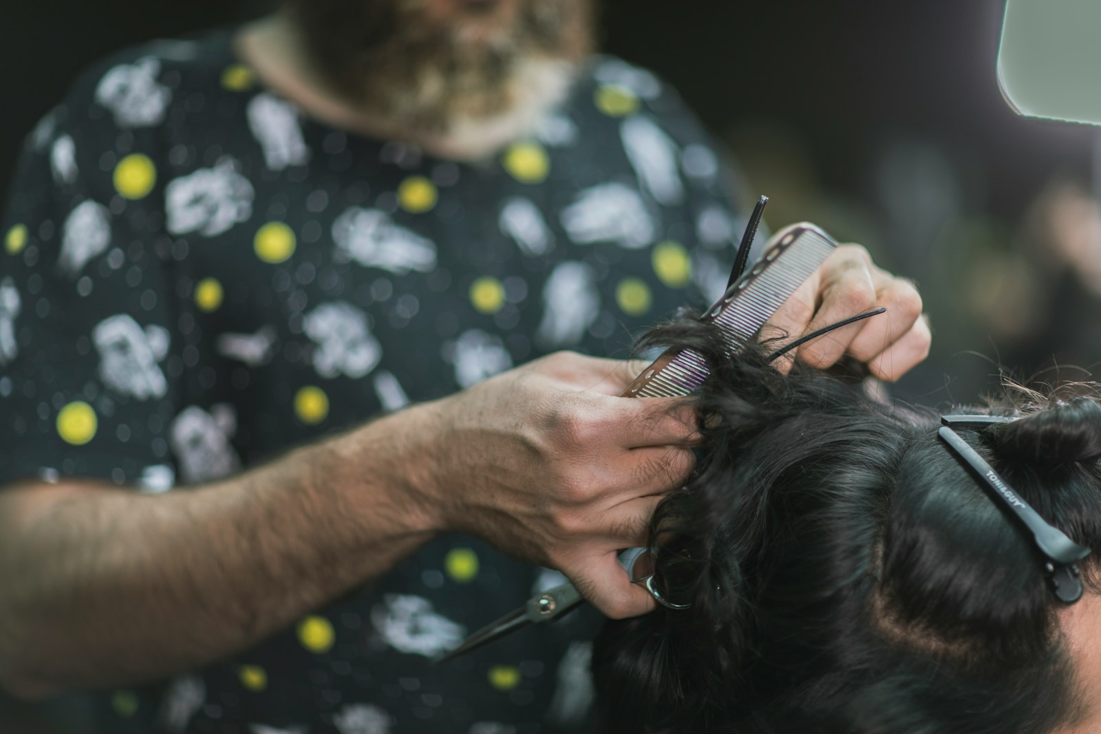 person in black and yellow shirt holding black and brown long coated small sized dog